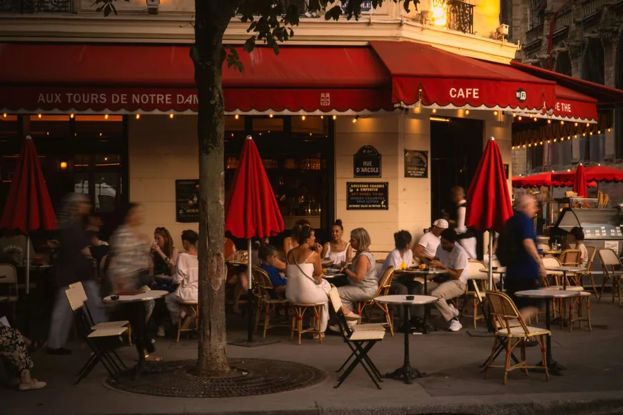 Golden evening light on a Paris café terrace with red awnings